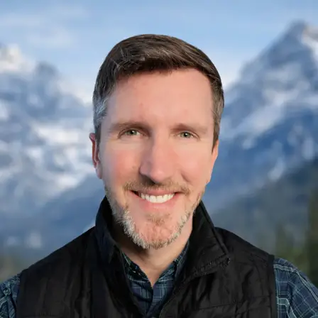 Zack Tomlin - Author, with mountain background, wearing a black vest